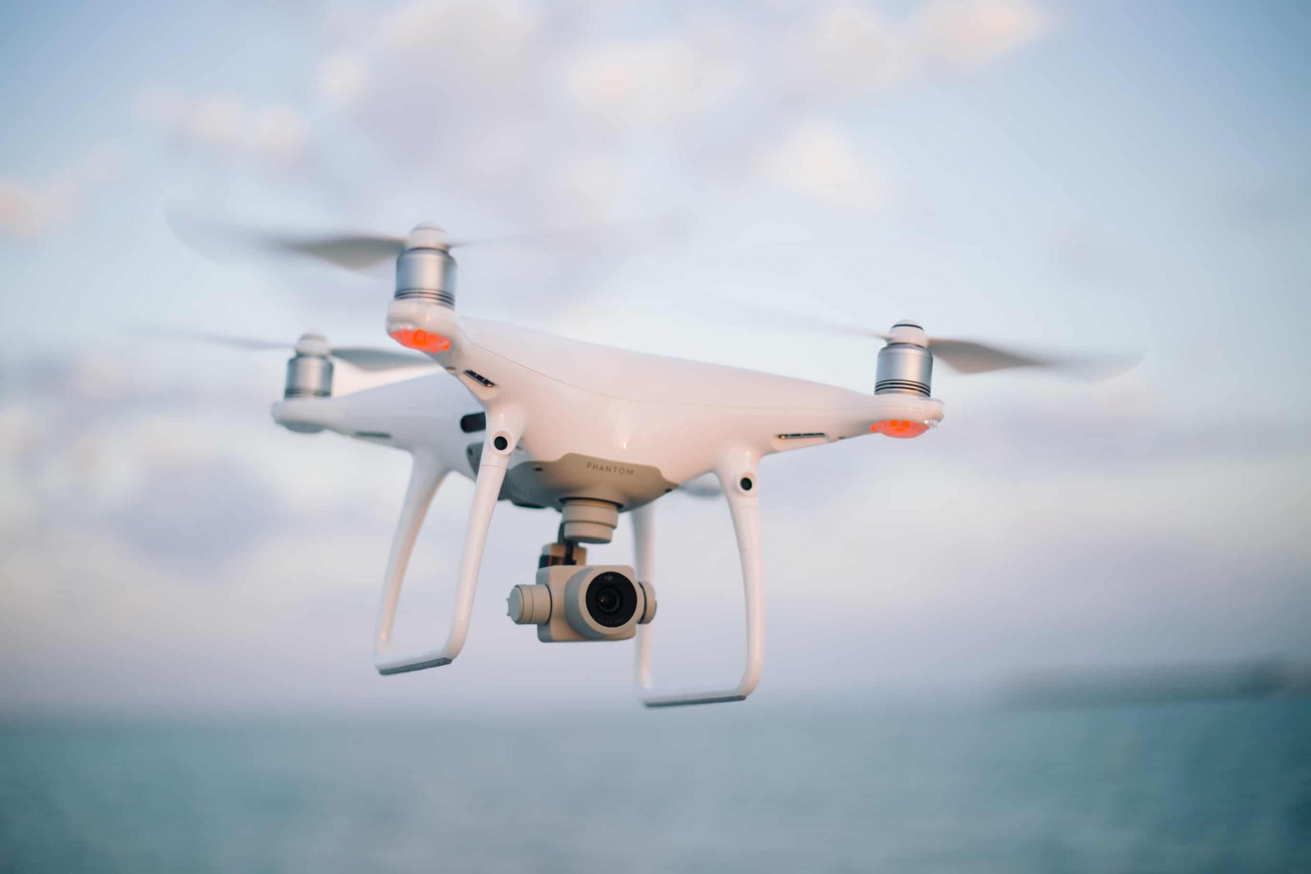 lietajici biely dron phantom 4 na rozostrenom pozadi
